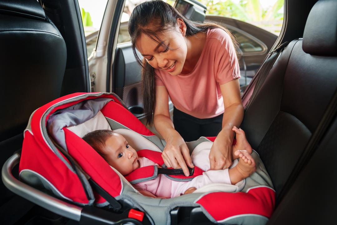 mom putting baby into car seat