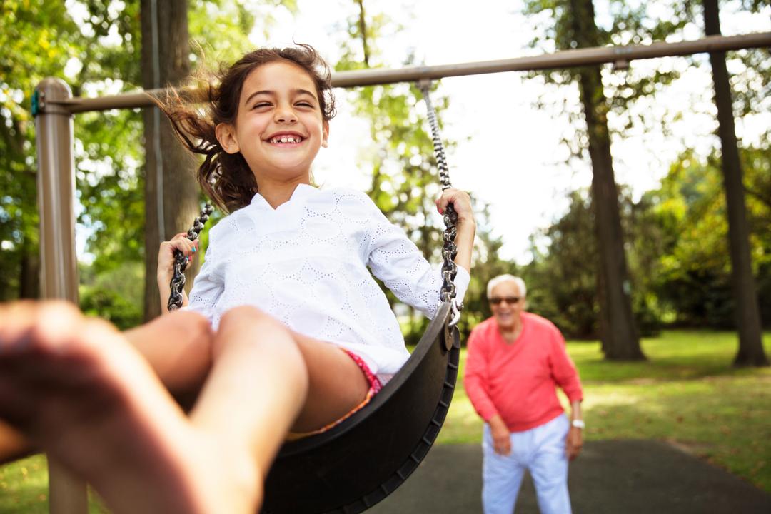 Child on a swing while grandparent stands behind to push