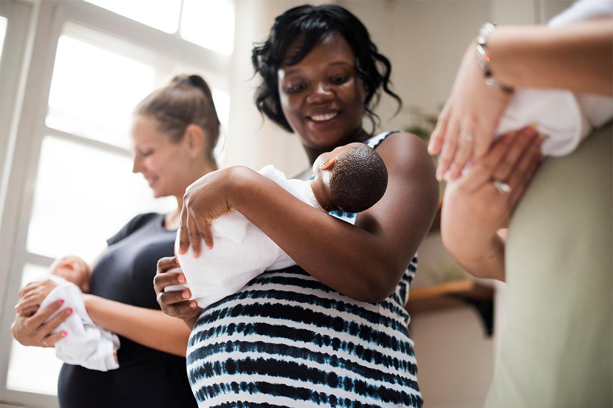 Three women cradling newborn babies