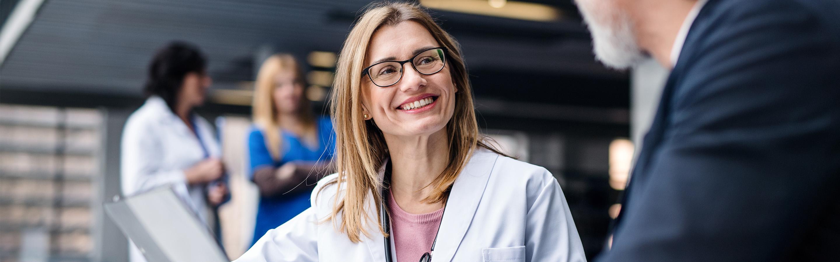 Female doctor smiling and talking to a man in a suit holding a clipboard