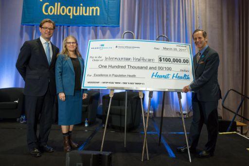 Two men and a woman standing around a giant cheque