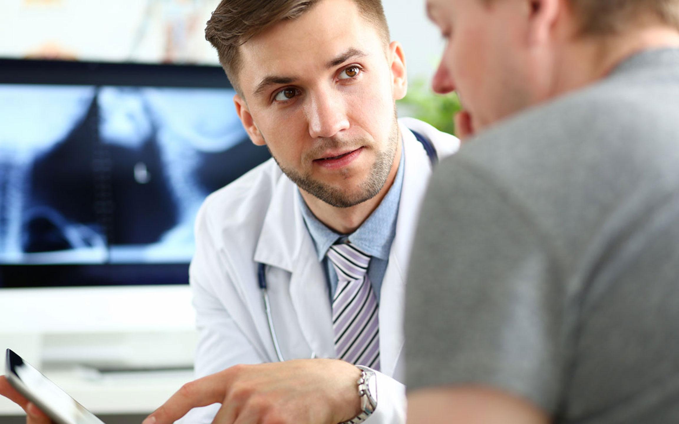 Male doctor showing results on a tablet device with a patient