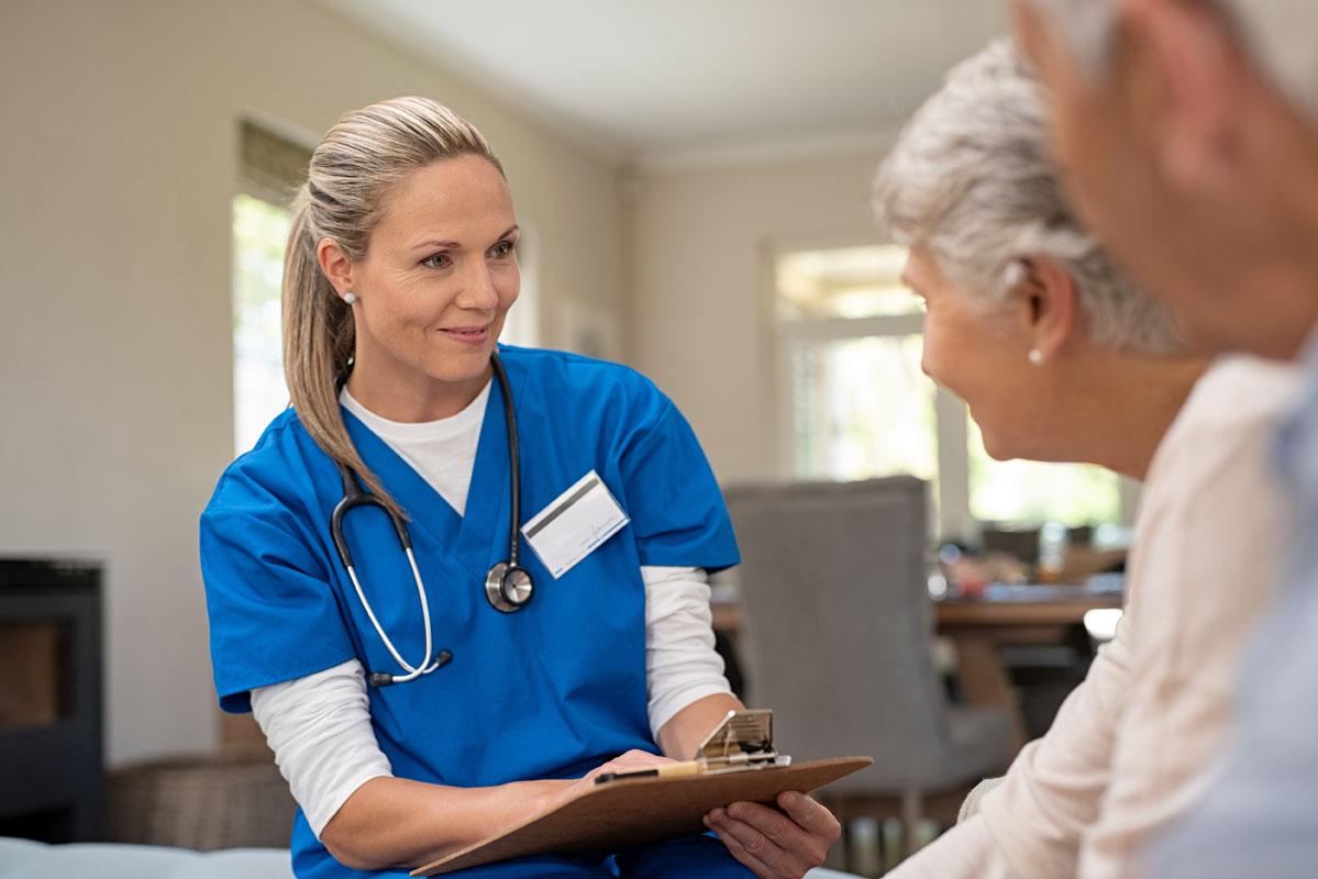 Happy nurse talking to senior patients in a private clinic