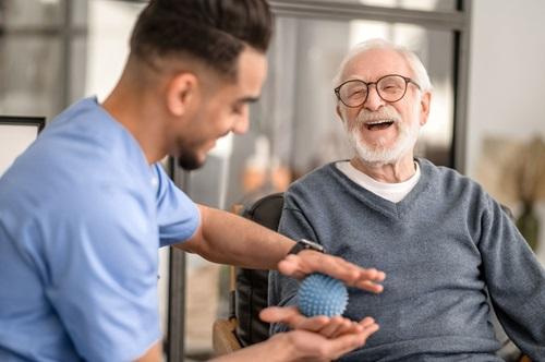 Happy elderly man undergoing a session of physical therapy conducted by a rehabilitation doctor