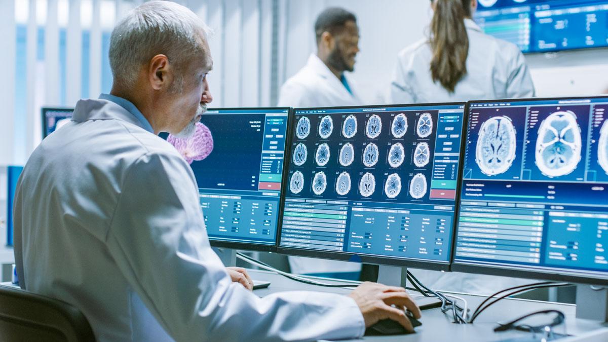 Senior medical research scientists looking at brain scans on computer screens