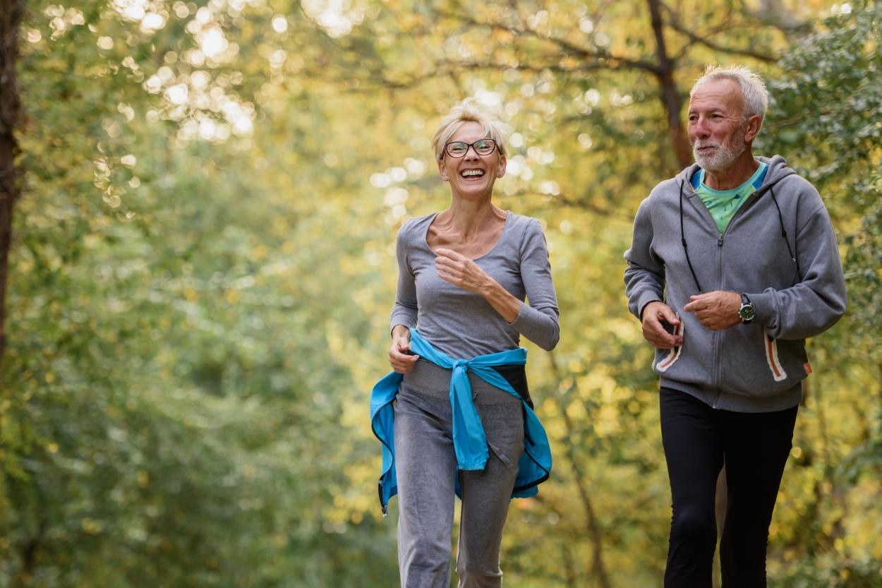 Two older people jogging in a forest