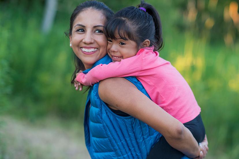 Woman giving a young girl a piggyback ride outdoors