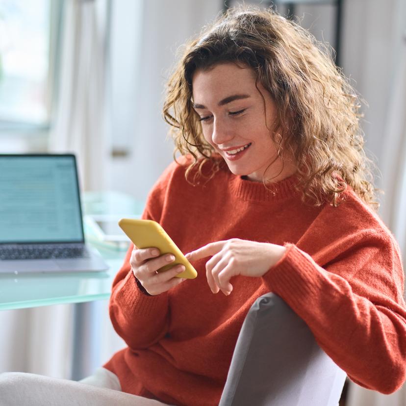 young woman sitting in office looking at phone